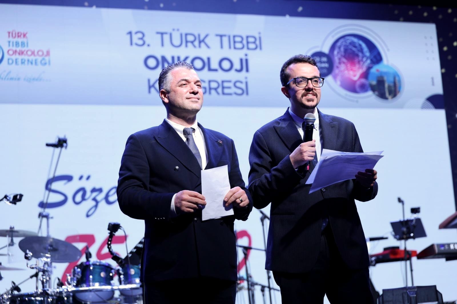 Doç. Dr. Deniz Can Güven, Türk Tıbbi Onkoloji Kongresi açılış oturumunda meslektaşıyla birlikte sahnede